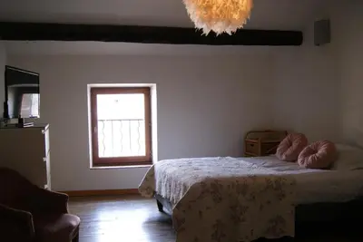 a bedroom with a bed and a window and a chandelier at La piscine de tonton Jean in Caunes-Minervois