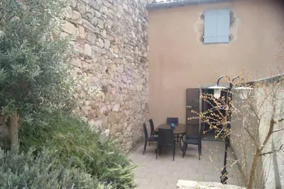 a patio with a table and chairs next to a wall at La piscine de tonton Jean in Caunes-Minervois