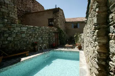a swimming pool in front of a stone building at La piscine de tonton Jean in Caunes-Minervois