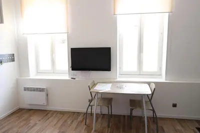 a living room with a table and a tv and two windows at Studio proche de la mer in Portel-des-Corbières