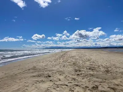 a sandy beach with waves and clouds in the sky at Studio proche de la mer in Portel-des-Corbières