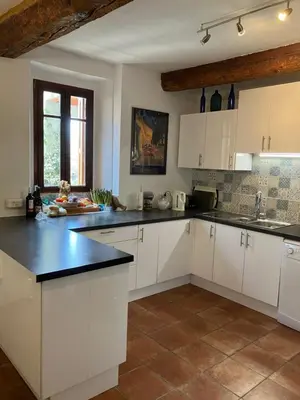 a kitchen with white cabinets and black counter tops at Le Sommet in Paziols