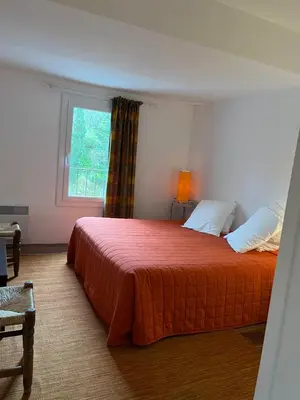 a bedroom with a bed with a red bedspread and a window at La maison d' Elizabeth in Lagrasse