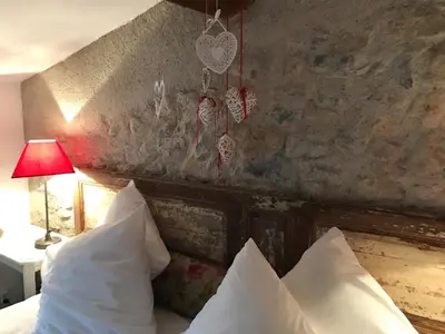 a bedroom with a bed with white pillows and a stone wall at La maison d' Elizabeth in Lagrasse