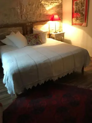 a bedroom with a white bed with a lamp on a table at La maison d' Elizabeth in Lagrasse