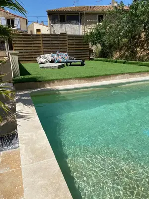 a swimming pool with blue water in a yard at Camin del Bosc in Roquefort-des-Corbières