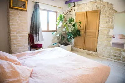 a bedroom with a bed and a stone wall at Camin del Bosc in Roquefort-des-Corbières