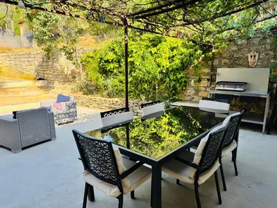 a black table with chairs and a garden in a patio at Camin del Bosc in Roquefort-des-Corbières