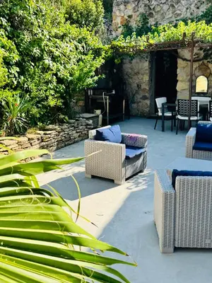 a patio with wicker chairs and a table and chairs at Camin del Bosc in Roquefort-des-Corbières