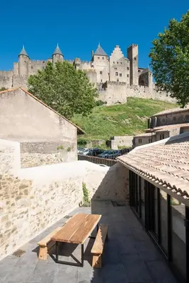 a wooden bench sitting on the side of a building with a castle at La terrasse de La Tour Pinte. in Carcassonne