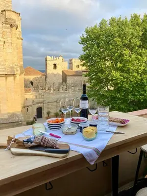 a table with a bottle of wine and wine glasses at Trésors de la Cathédrale, Maison de Ville sur 4 niveaux in Narbonne
