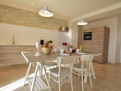 a kitchen with a wooden table with chairs and a counter at Cozy Escape in Villesèque in Villesèque-des-Corbières