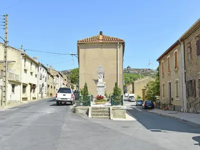 a street with a statue in the middle of a town at Blissful Stay in Mandourelle in Villesèque-des-Corbières