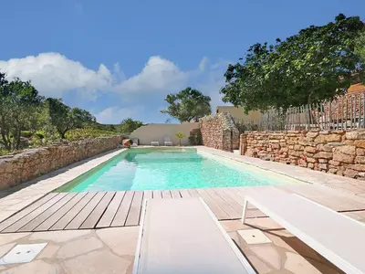 a swimming pool next to a stone wall at Serene Family Escape in Villesèque-des-Corbières