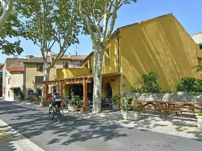 a person riding a bike in front of a yellow building at Serene Family Escape in Villesèque-des-Corbières