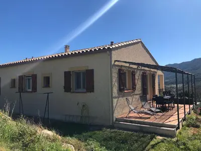 a house with a deck and a table and chairs at Gîte San Jordi in Duilhac