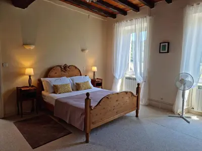 a bedroom with a large bed and two windows at Domaine de Pouroutounat in Mirepoix