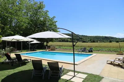 a swimming pool with chairs and umbrellas at Domaine de Pouroutounat in Mirepoix