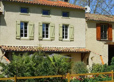 a house with green shuttered windows and a fence at Domaine de Pouroutounat in Mirepoix