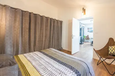 a bedroom with a bed and a window with curtains at L'urbain Narbonnais in Narbonne