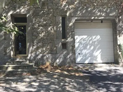 a garage with a door and a window next to a building at le verso in Narbonne
