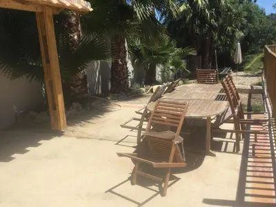 a wooden table and chairs in a patio with palm trees at le verso in Narbonne