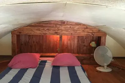 a bedroom with a bed with two pillows and a fan at Location Nuit Studio Port Gruissan in Gruissan