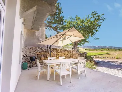 a white table and chairs with an umbrella at Classy Apartment in Villesèque-des-Corbières with Swimming Pool in Villesèque-des-Corbières