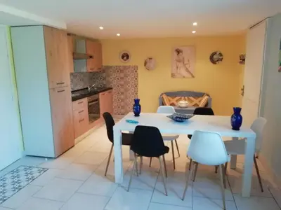 a kitchen and dining room with a white table and chairs at Gîte le pastel in Puéchoursi