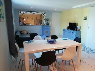 a dining room and living room with a table and chairs at Gîte le pastel in Puéchoursi