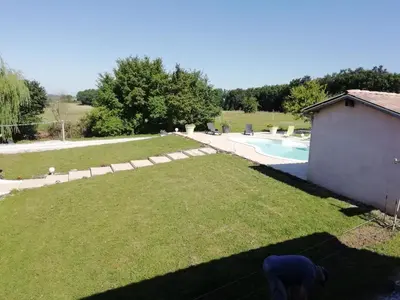 a dog standing in a yard next to a pool at Gîte le pastel in Puéchoursi