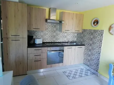 a kitchen with wooden cabinets and a stove top oven at Gîte le pastel in Puéchoursi