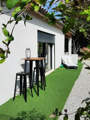 a fake grass yard with a table and stool at La Villa Claudia Jardin et Spa in Pennautier