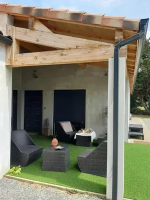 a patio with a wooden pergola with furniture and grass at La Villa Claudia Jardin et Spa in Pennautier