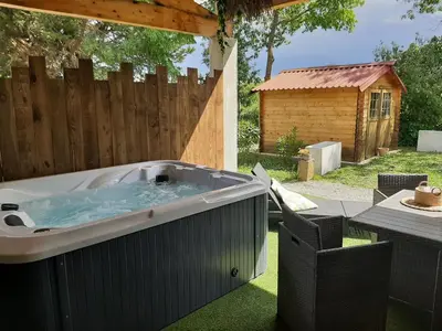 a hot tub in a backyard with a wooden fence at La Villa Claudia Jardin et Spa in Pennautier