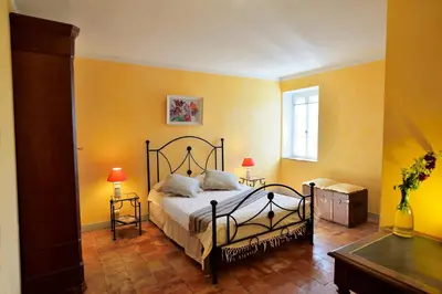 a bedroom with a bed and two tables and a window at Le village-hôtes in Sainte-Vallière