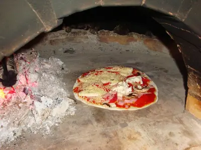 a pizza is cooking in a pizza oven at Le village-hôtes in Sainte-Vallière
