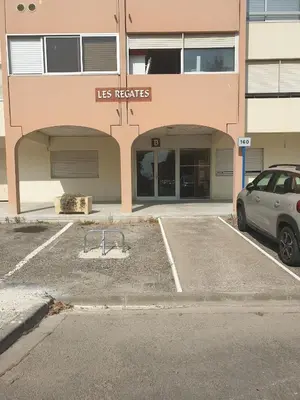 a car parked in a parking lot in front of a building at Studio plage du Grazel in Gruissan