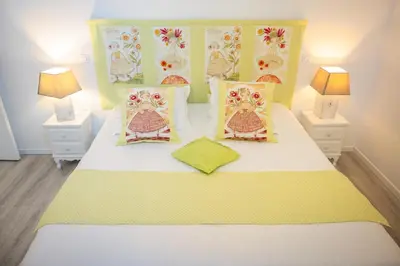a bedroom with a white bed with yellow and pink pillows at Le Gite des Jardins de Mazamet in Mazamet