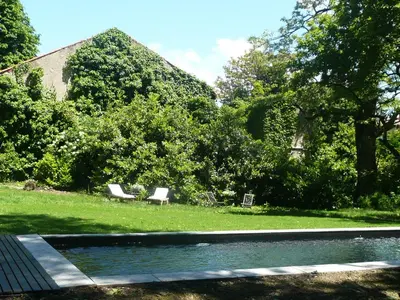 a swimming pool with two white chairs in a yard at Le Gite des Jardins de Mazamet in Mazamet
