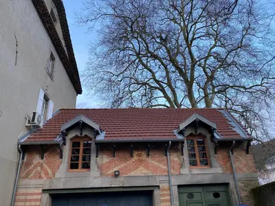 a brick house with a brown roof next to a building at Le Gite des Jardins de Mazamet in Mazamet