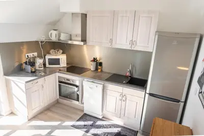 a kitchen with white cabinets and a refrigerator at Le Gite des Jardins de Mazamet in Mazamet