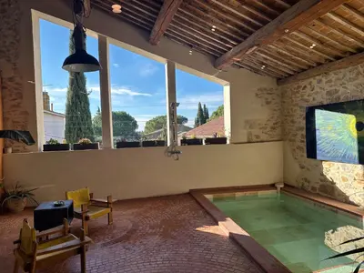 a swimming pool in a room with a large window at La Remise Penthouse in Le Somail