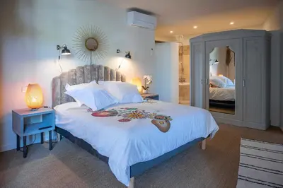a bedroom with a large bed and a mirror at La Remise Penthouse in Le Somail
