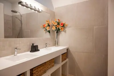 a bathroom with two sinks and a vase of flowers at La Remise Penthouse in Le Somail