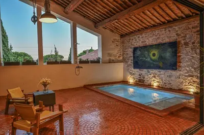 an indoor pool in a room with a stone wall at La Remise Penthouse in Le Somail