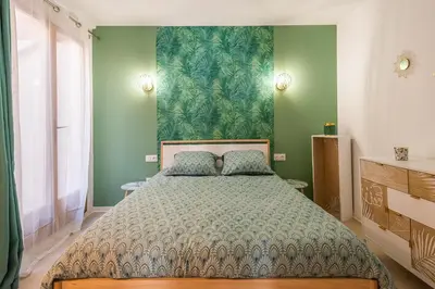 a bedroom with a large bed with green walls at L'Exotique Narbonnais in Narbonne