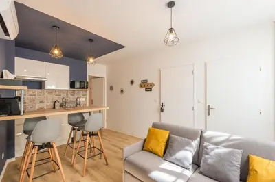 a living room with a couch and a kitchen at Le Cosy Narbonnais in Narbonne