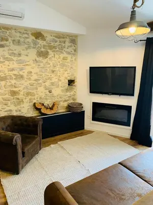 a living room with a flat screen tv on a stone wall at L'atypique, La Vue et le Standing du 36 ! Emplacement, clim et extérieur ! in Carcassonne