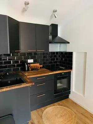 a kitchen with black cabinets and a sink at L'atypique, La Vue et le Standing du 36 ! Emplacement, clim et extérieur ! in Carcassonne